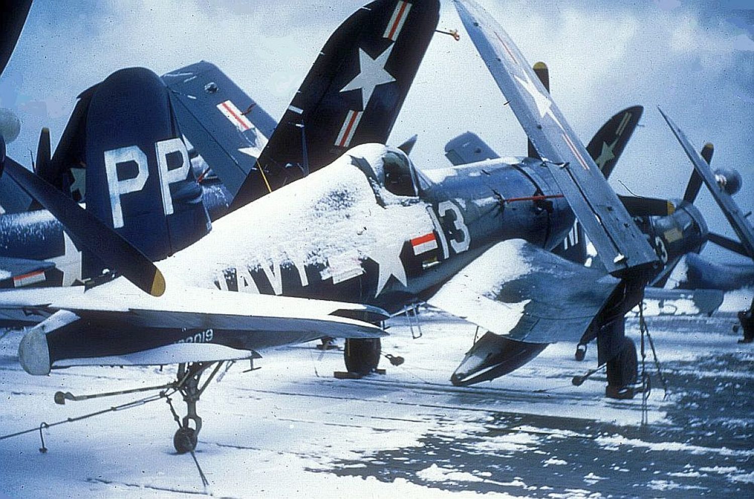 A snow covered VC-61 Vought F4U-4P with a VC-3 F4U-5N Corsair forward on a CV during the winter of 1950-51 in Korean waters. Tailhook Association